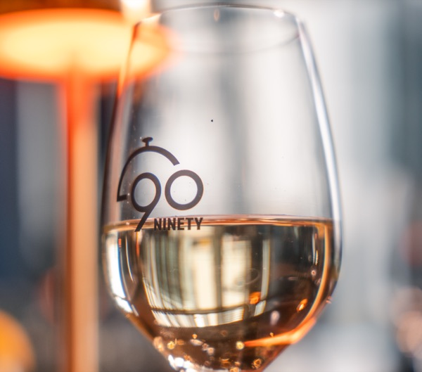 Glas witte wijn met het Ninety-logo